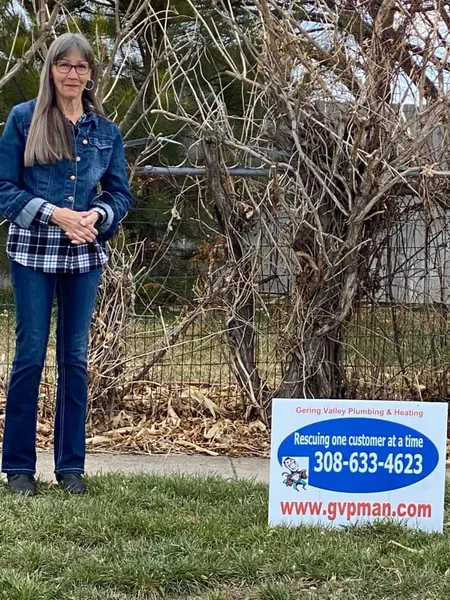 March yard-sign winner Mary with their Gering Valley Plumbing & Heating sign