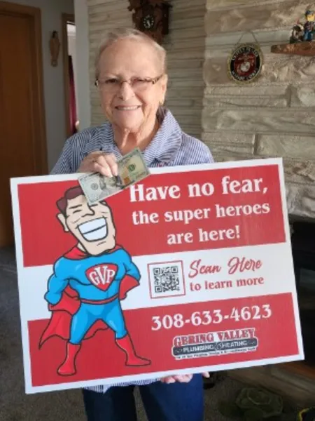 April yard-sign winner Barb with their Gering Valley Plumbing & Heating sign